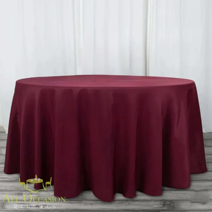 132 Inch Round Polyester Tablecloth Burgundy draped elegantly over a large round table, perfect for all occasions.
