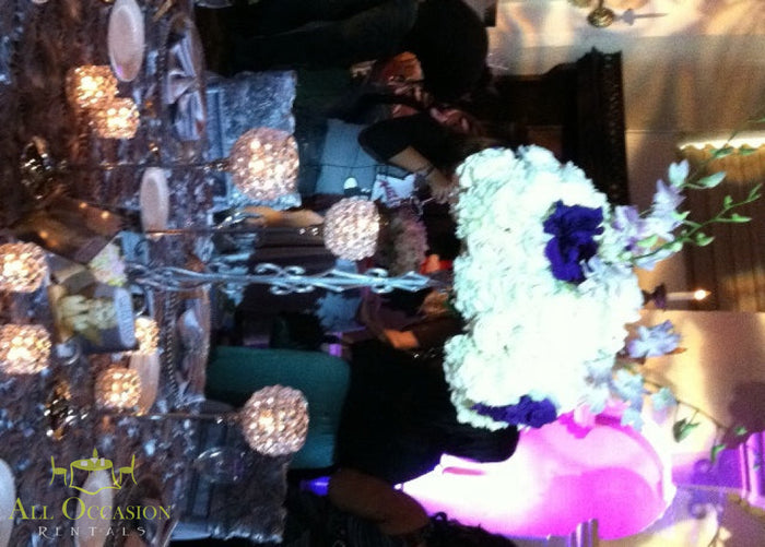 Elegant centerpiece flower rentals featuring white and purple blooms at a beautifully set table for an event.