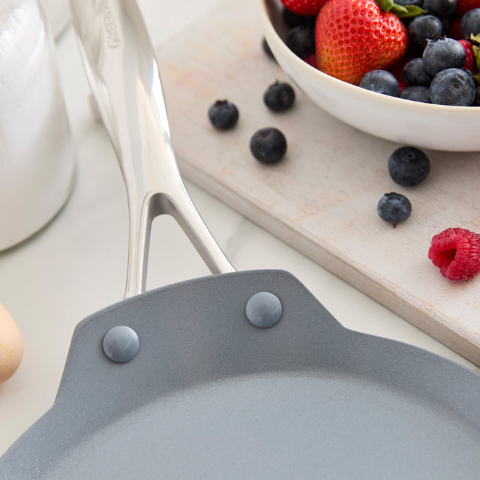 Gray ceramic nonstick crepe pan next to a bowl of strawberries, blueberries, and raspberries.