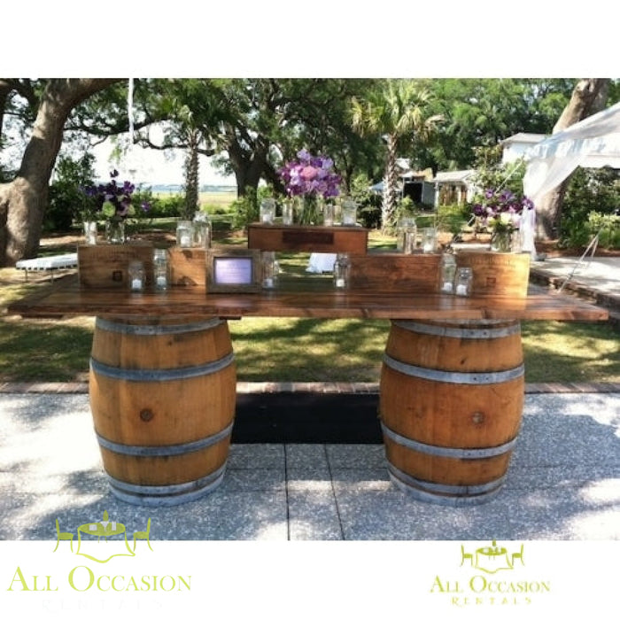 Beautiful wine barrel bar or table set up outdoors with floral arrangements.
