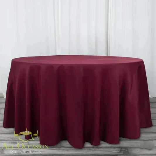 132 Inch Round Polyester Tablecloth Burgundy draped elegantly over a large round table, perfect for all occasions.