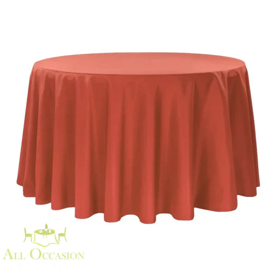 132 inch round polyester tablecloth burnt orange displayed on a large round table.