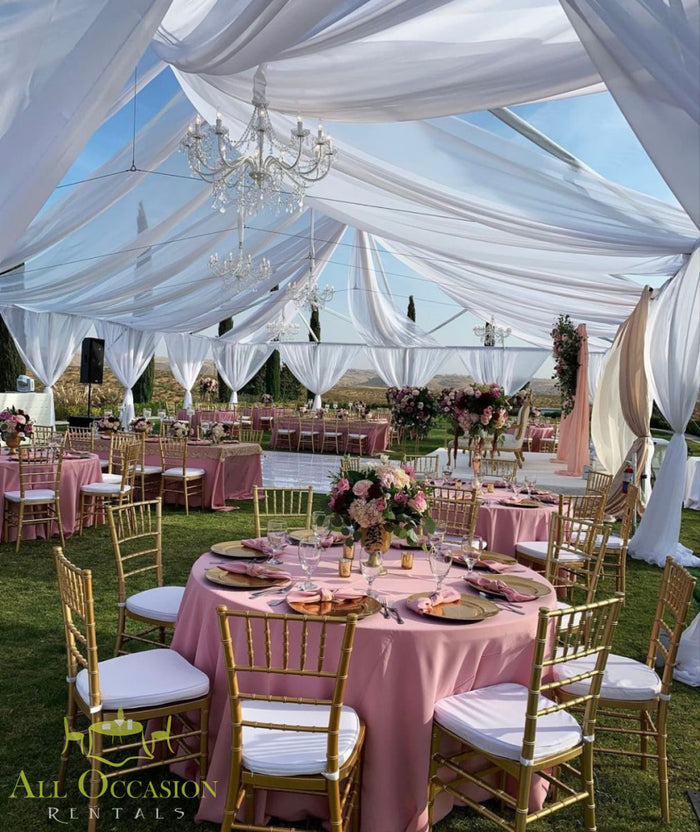 Elegant outdoor reception with pink table linens, chiavari chairs, and crystal chandelier for event rentals in Corona.