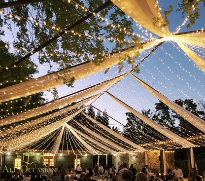 Bistro Lighting Rental 37.5ft white string lights illuminating an event tent, creating a warm atmosphere for gatherings.
