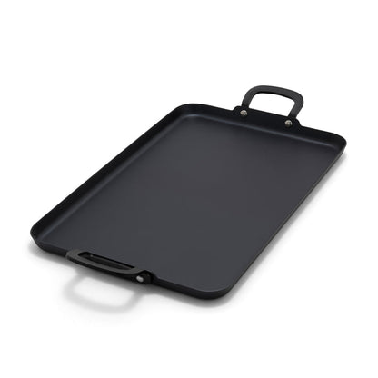 Carbon steel double burner griddle with two handles on a white background.