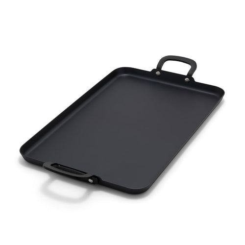 Carbon steel double burner griddle with two handles on a white background.