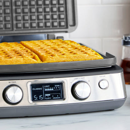 Ceramic nonstick 4-square waffle maker in graphite with digital settings, on a kitchen counter.