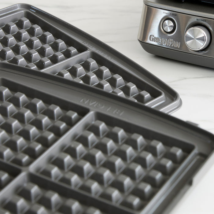 Close-up of two grid-patterned waffle plates for the Elite Ceramic Nonstick 4-Square Waffle Maker | Premiere Stainless Steel, perfect for crafting Liège waffles, shown beside its stainless steel body and control knobs.