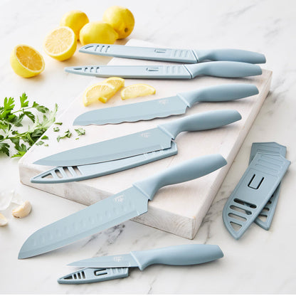 Blue six-piece cutlery set on a white cutting board with lemons, parsley, and garlic nearby.