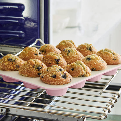 Muffins in a pink muffin pan sitting on an oven rack