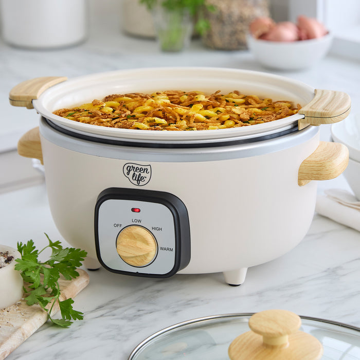 Cream slow cooker with food inside on a marble countertop