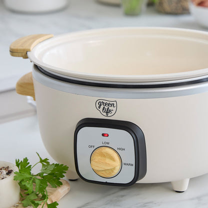Cream slow cooker with a control knob on a light surface