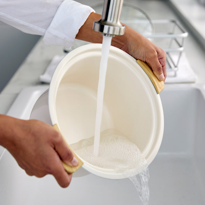 Person washing a bowl with running water from a faucet