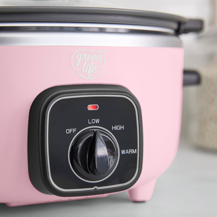 Pink slow cooker with control knob on a light gray background