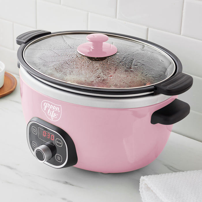 Pink slow cooker with a glass lid on a white countertop