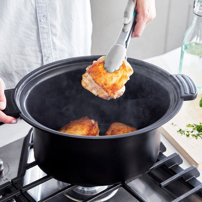 Person using tongs to remove fried chicken from a pot on a stove.