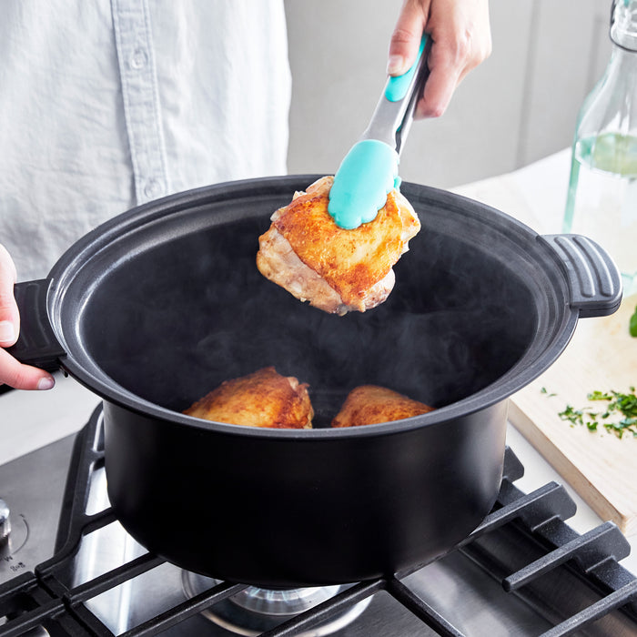 Person using tongs to remove fried food from a pot on a stove.