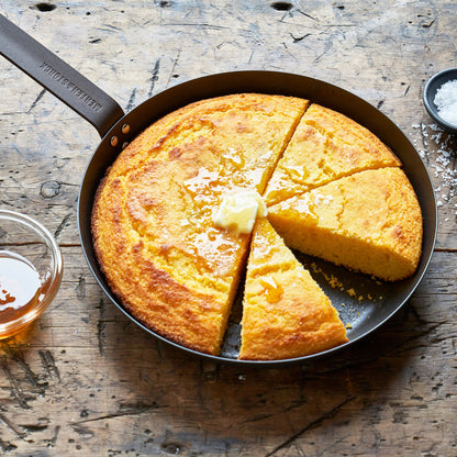 Cornbread slices in a Merten  Storck carbon steel frypan, served with butter and honey on top.