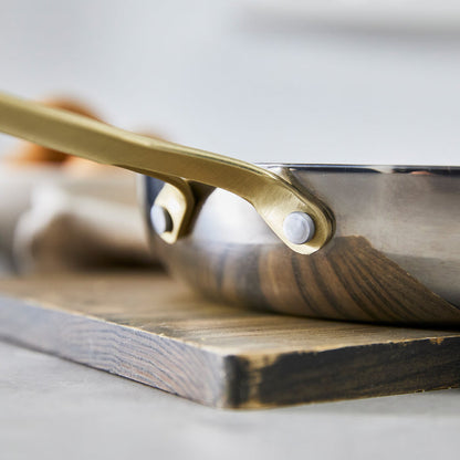 Stainless steel frypan set, 10-inch and 12-inch sizes, on a wooden cutting board.