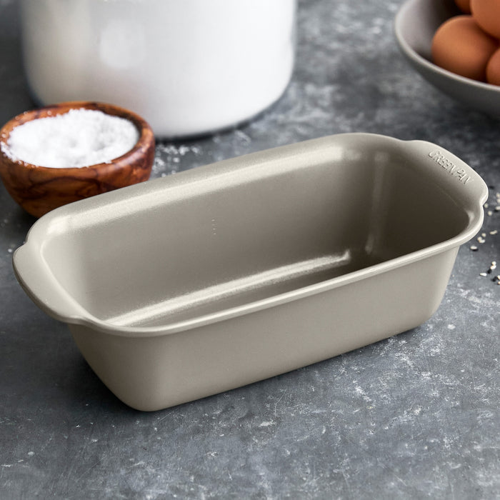 Taupe ceramic loaf pan on gray counter with eggs, salt, and a ceramic jar nearby.