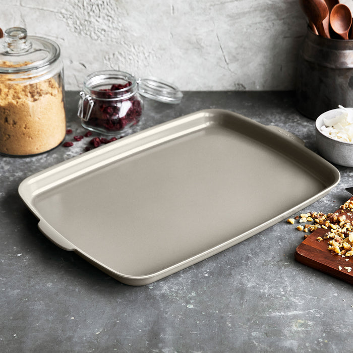 Taupe ceramic nonstick sheet pan set, two 18x13 pans with smooth finish, shown side by side.