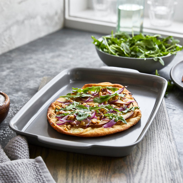 Flatbread pizza topped with arugula and cheese on a light-colored ceramic nonstick 13x9 quarter sheet pan.