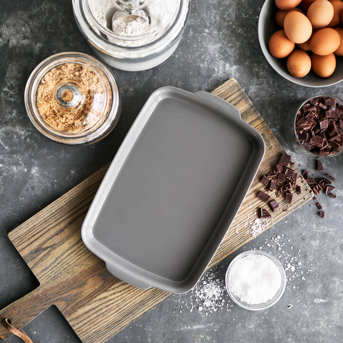 Gray ceramic nonstick quarter sheet pan set, 13x9, shown with baking ingredients on a wooden board.
