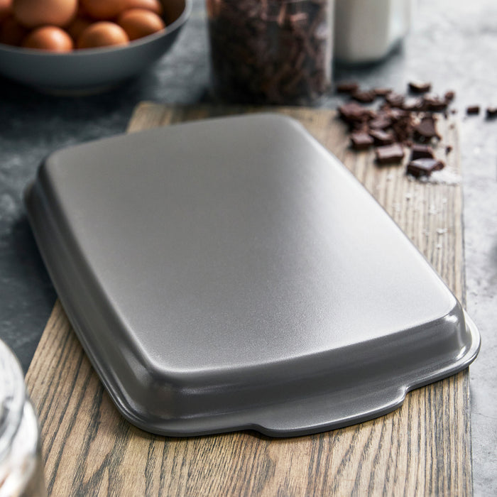 Gray ceramic nonstick sheet pan set of two on a board, with eggs and chocolate nearby.