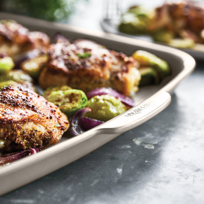 Ceramic taupe sheet pan with baked chicken thighs, Brussels sprouts, and onions.