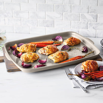 Ceramic nonstick 6-piece bakeware set in taupe with roasted chicken, carrots, onions, and a plate nearby.