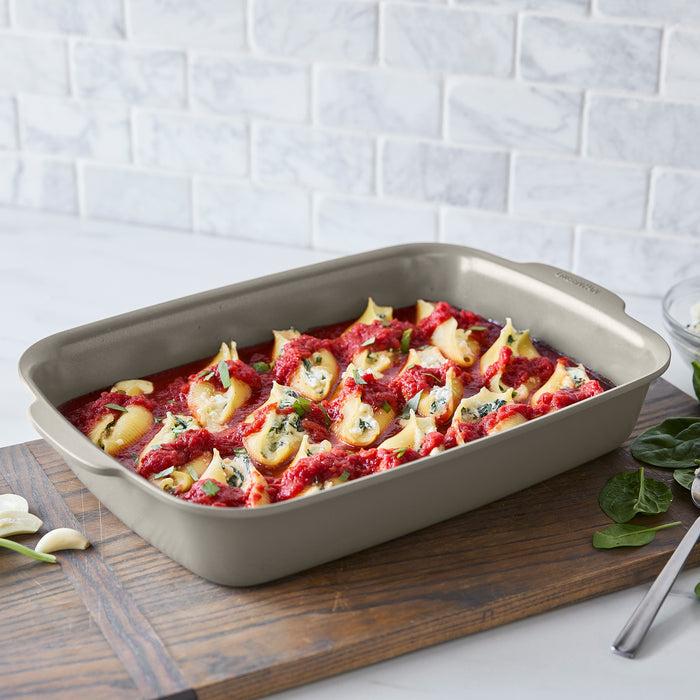 Ceramic taupe Premiere Ovenware 6-piece set with stuffed pasta shells topped with sauce, on a wooden board.