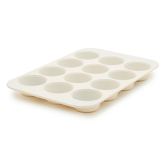 Cream 12-cup muffin pan displayed at an angle on a plain background.