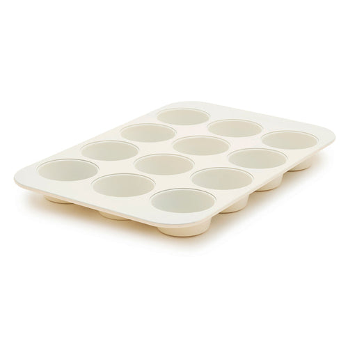 Cream 12-cup muffin pan displayed at an angle on a plain background.