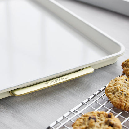 Cream half sheet pan with matching cooling rack, both holding cookies on a gray countertop.
