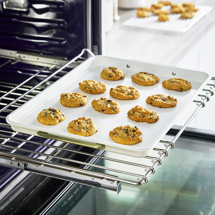 Chocolate chip cookies on a cream half sheet pan and matching cooling rack.