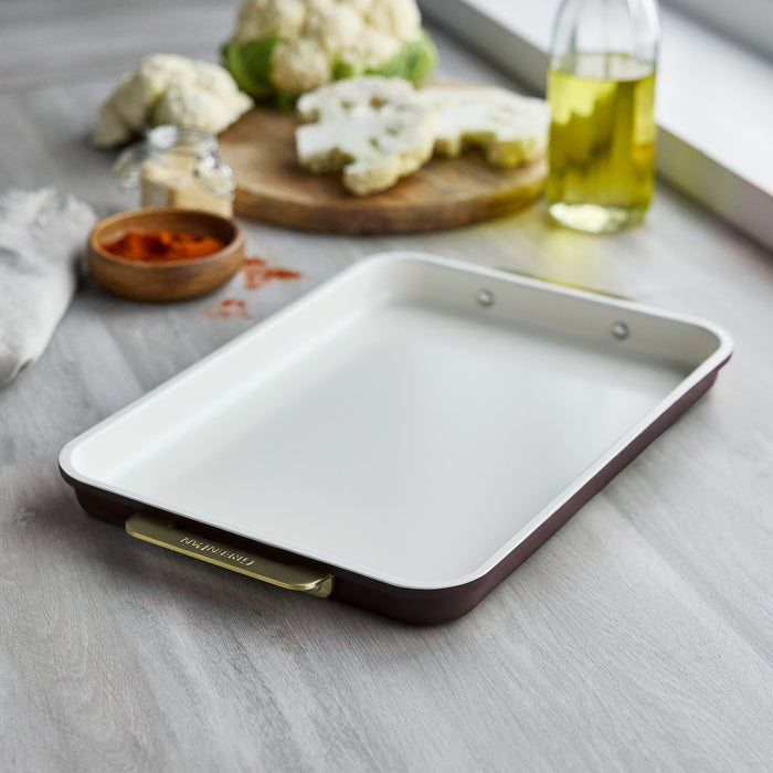 Reserve 13″ x 9″ quarter sheet pan in dark red aluminized steel with a cream interior and gold-tone handles.