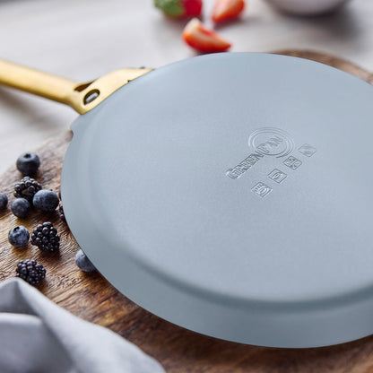 Blue crepe pan on a wooden surface with berries and a blurred background