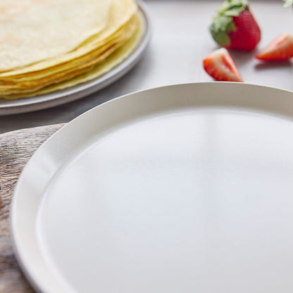 Close-up of a crepe pan with strawberries in the background