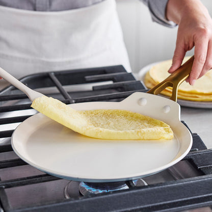 Person making crepes on a gas stove with a spatula