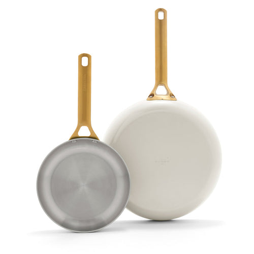 Two frying pans with gold handles on a white background
