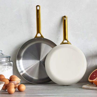 Two frying pans with gold handles on a kitchen counter.