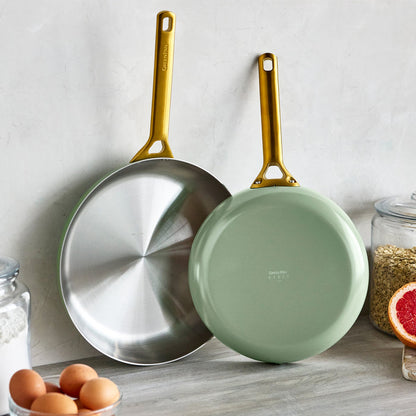 Two frying pans with gold handles on a kitchen counter.