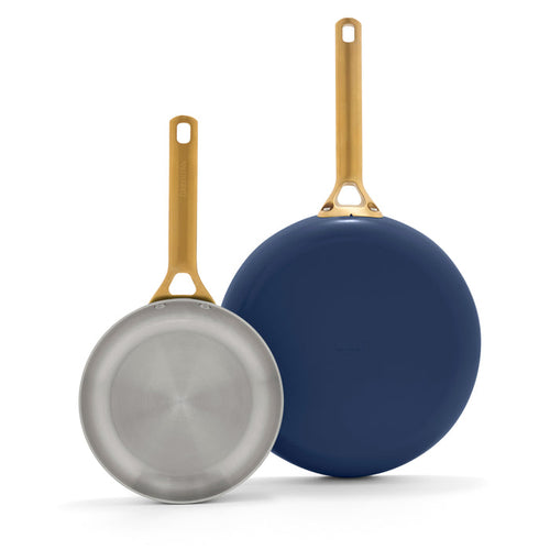 Two frying pans with gold handles on a white background