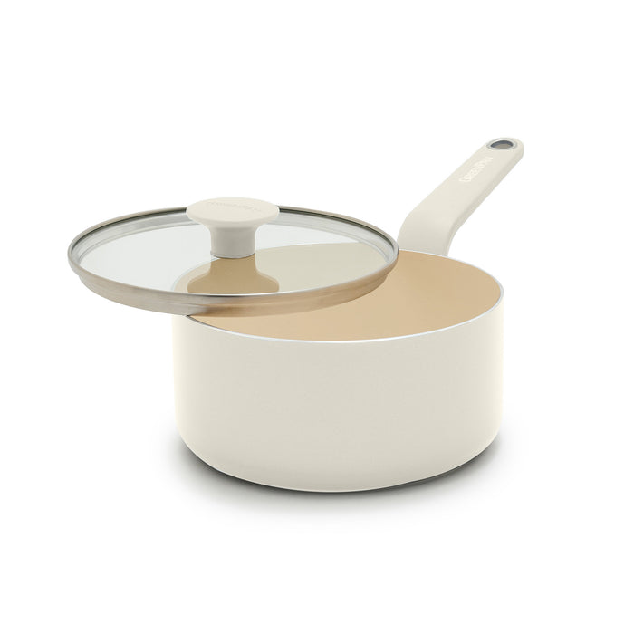 Cream ceramic 2-quart saucepan with long handle and smooth finish, shown with a glass lid slightly ajar.