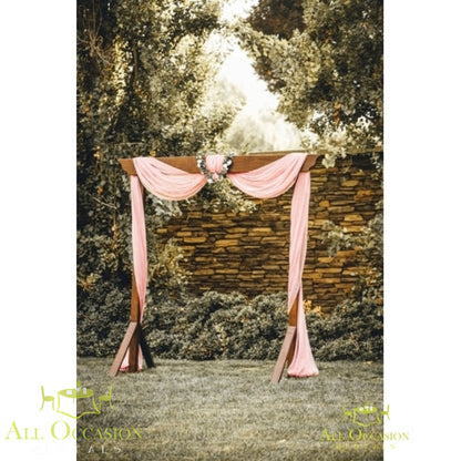 Rustic wood wedding arch decorated with draping in outdoor setting, ideal for events and rentals in Corona.