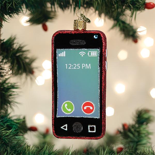 A Christmas tree ornament shaped like a smartphone hangs among green branches and twinkling lights. The ornament displays a screen with call icons and the time 12:25 PM.