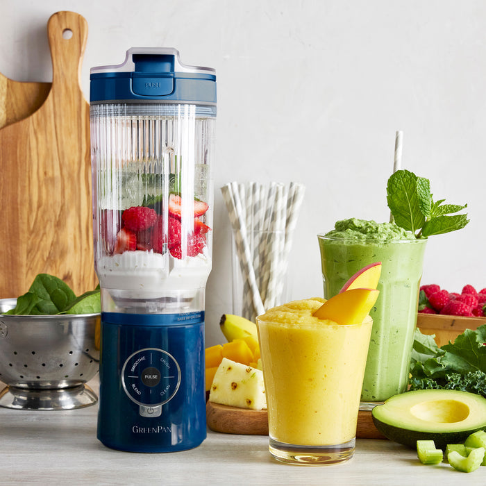 Blue blender with ingredients and two smoothies on a table