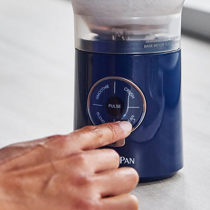 Blue blender with control panel being operated by a hand on a light background