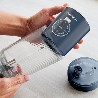 Hands assembling a blue Spin  Go portable blender, showing the control panel and clear jar on a light-colored surface.
