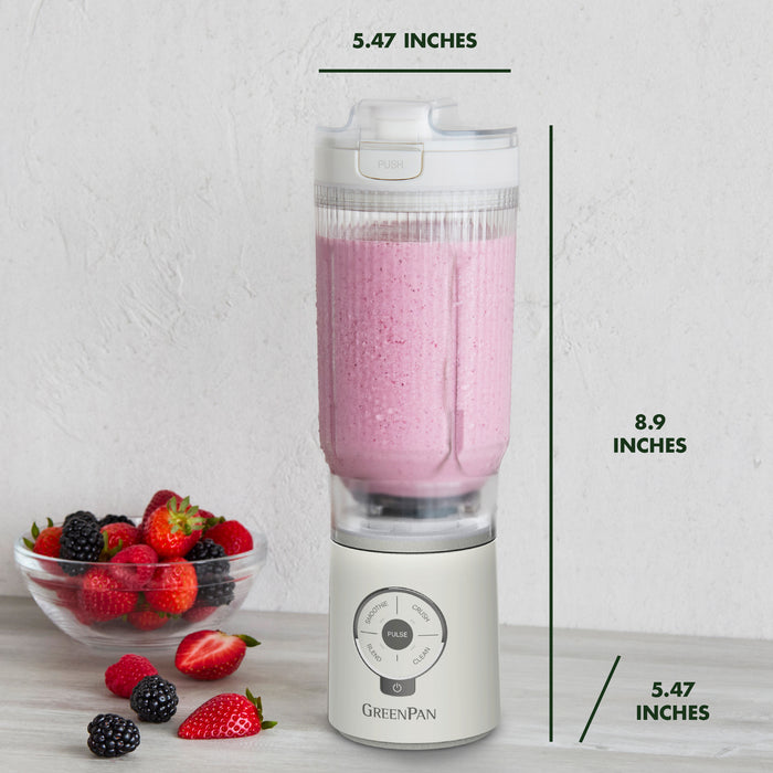 Blender with a pink smoothie and berries on a white surface, with measurements indicated.